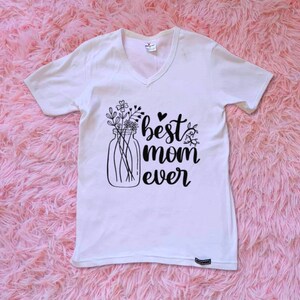 Op de afbeelding: Wit T-shirt met een zwarte afbeelding van een glazen pot gevuld met bloemen en de tekst "best mom ever".