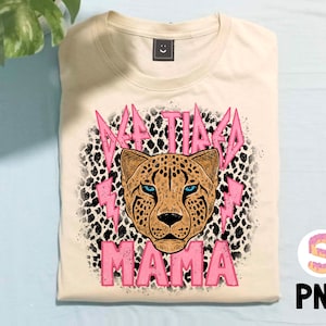May include: A beige t-shirt featuring a pink cheetah print and the text "Taco Mama" in pink lettering.
