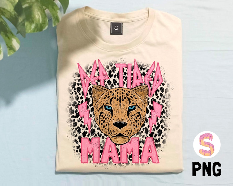 May include: A beige t-shirt featuring a pink cheetah print and the text "Taco Mama" in pink lettering.