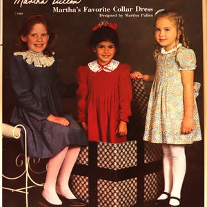 May include: An image of a vintage sewing pattern featuring three young girls in dresses. The dresses have collars and are in blue, red, and floral patterns. The text reads "Martha's Favorite Collar Dress" and "Sizes Regular 4-12 years."