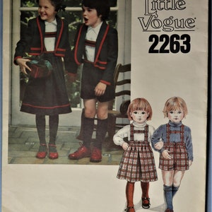 May include: Vintage Little Vogue 2263 sewing pattern. The cover features illustrations of children in coordinated outfits. The outfits include jackets, shorts, skirts, and jumpers in dark colors with red trim. The pattern is for children's clothing.