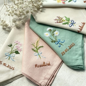 Peut inclure: Quatre mouchoirs brodés avec des motifs floraux et des dates. Les mouchoirs sont dans des tons de blanc, rose, vert et beige. Les dates sont 29.05.2025, 05.10.2025, Adelaide et Rosalind.