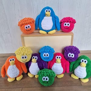 May include: A collection of colorful crocheted penguin toys. The penguins are in various colors, including orange, yellow, green, blue, purple, and red. Some of the penguins have white faces and bellies.