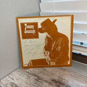 May include: A vintage vinyl record album cover featuring a photo of country music singer Tommy Jennings. The album title is "Then There Was One". The cover is brown and features a photo of Jennings wearing a cowboy hat and holding a guitar. The album cover is signed by Jennings.