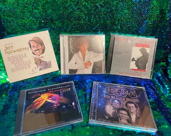 May include: Five compact discs with various artists and album titles. The titles include "The Best of Jeff Foxworthy", "Reba", "Classic Cash", "Mannheim Steamroller Christmas Live", and "Christmas with the Gatlin Brothers".