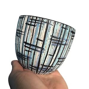 May include: A blue and white ceramic planter with a geometric pattern. The planter is in the shape of a bowl and has a black rim.