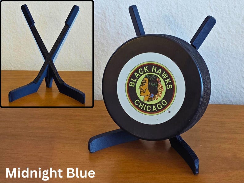 May include: A midnight blue hockey puck display stand. The stand is designed to hold a hockey puck, with a Chicago Blackhawks logo. The stand is made of a midnight blue material and has a unique design.