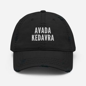 以下が含まれることがあります： 白い刺繍で「AVADA KEDAVRA」と書かれた、黒のダメージ加工されたベースボールキャップです。