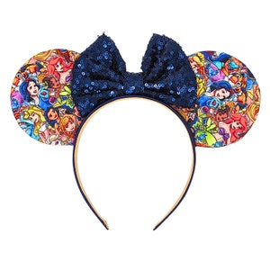 Puede incluir: Un par de orejas de ratón azules y blancas con un lazo de lentejuelas azules. Las orejas están cubiertas con un estampado de princesas Disney.