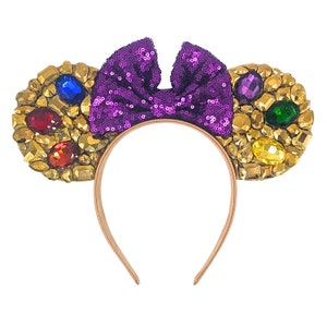 May include: Purple sequined bow headband with gold and jewel-toned embellishments on each side.