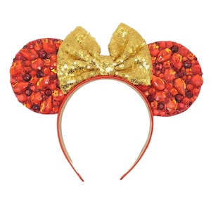 May include: Red and gold Minnie Mouse ears headband with a large gold bow and red jeweled ears.