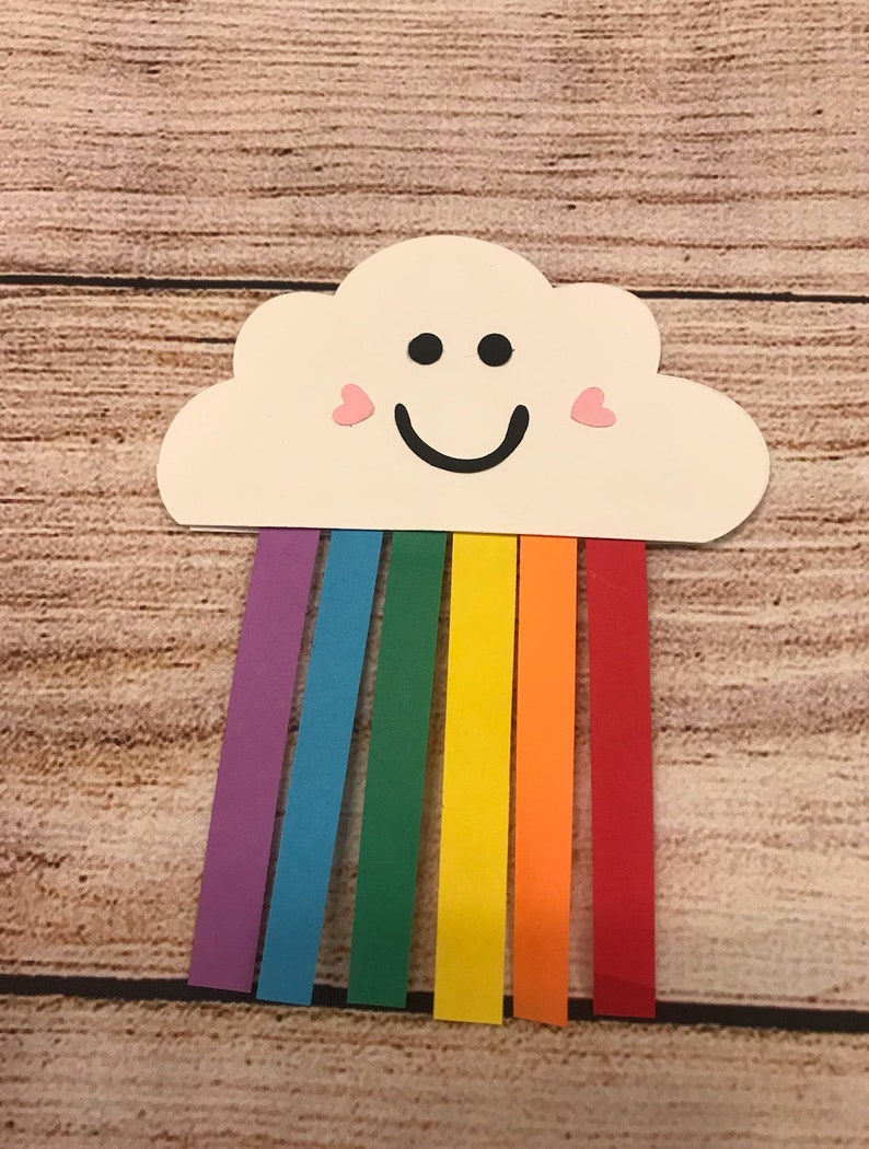 May include: A white paper cloud with a smiling face and pink hearts for cheeks, with a rainbow of coloured paper strips hanging from the bottom.