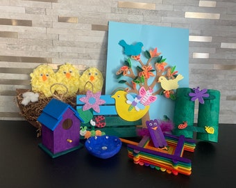May include: A spring-themed craft project with a variety of handmade items, including a birdhouse, a bird feeder, a nest with chicks, a tree with birds, and a dragonfly. The items are made from paper, cardboard, and other materials.