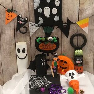 May include: A collection of Halloween crafts, including a black felt bat, a witch's cauldron, a ghost made from a paper towel roll, a pumpkin made from a paper plate, and a ghost made from a toilet paper roll. The crafts are decorated with googly eyes, glitter, and other embellishments.
