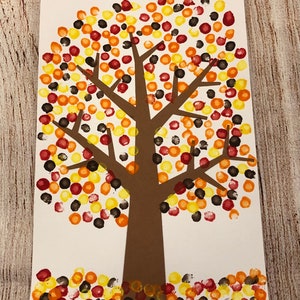 May include: A brown paper tree with a brown trunk and branches. The tree is decorated with red, orange, yellow, and black dots, resembling fall leaves.