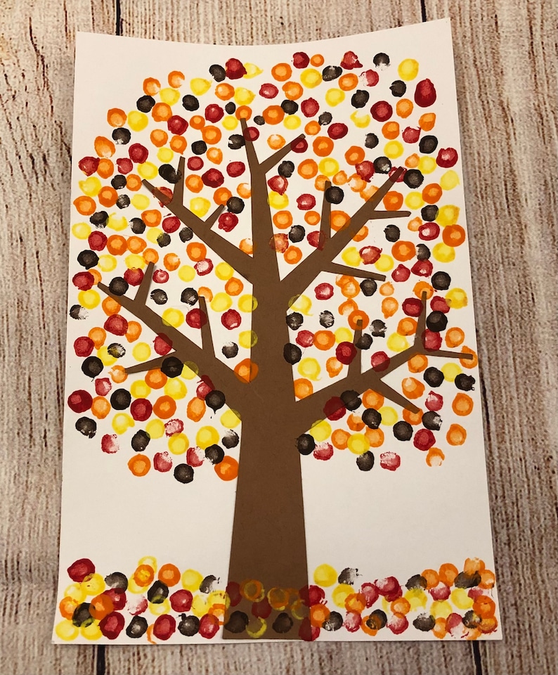 May include: A brown paper tree with a brown trunk and branches. The tree is decorated with red, orange, yellow, and black dots, resembling fall leaves.