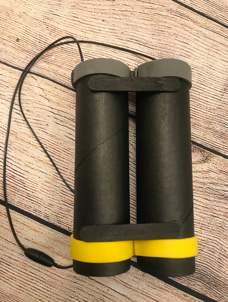 Peut inclure: Jumelles en carton noir avec une bordure jaune et un cordon noir.
