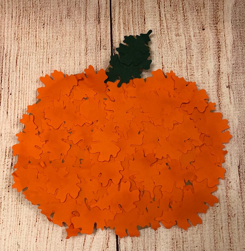 May include: A large orange pumpkin made of paper leaves. The pumpkin has a green leaf stem.