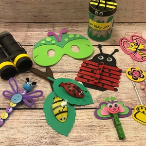 Peut inclure: Une collection d'artisanat sur le th&egrave;me des insectes, comprenant une coccinelle en b&acirc;tonnets de sucettes, un papillon aux ailes roses, un masque d'insecte vert, une libellule en cure-pipes, une abeille dans une feuille et un bocal &agrave; insectes avec des yeux globuleux.