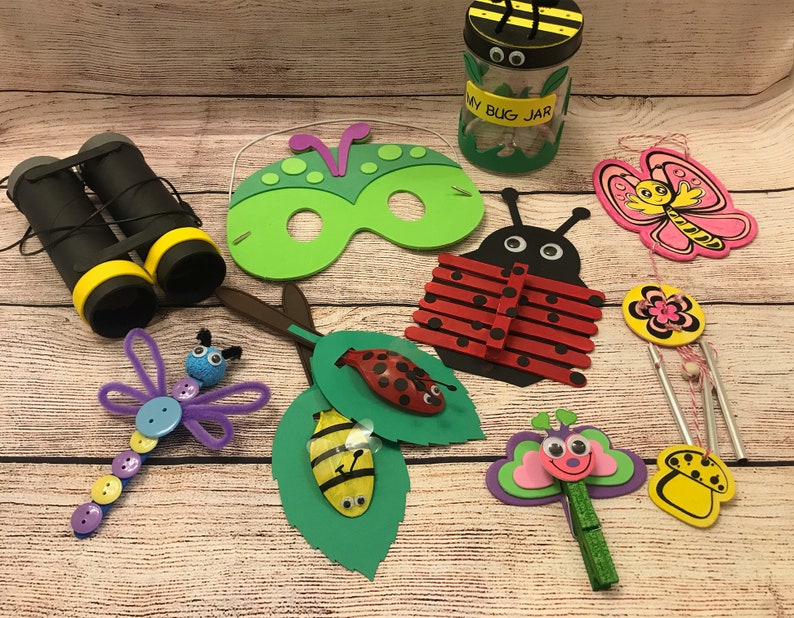 Peut inclure: Une collection d'artisanat sur le th&egrave;me des insectes, comprenant une coccinelle en b&acirc;tonnets de sucettes, un papillon aux ailes roses, un masque d'insecte vert, une libellule en cure-pipes, une abeille dans une feuille et un bocal &agrave; insectes avec des yeux globuleux.