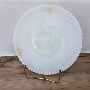 May include: A white milk glass serving bowl with a scalloped edge and gold floral accents. The bowl is on a metal stand.