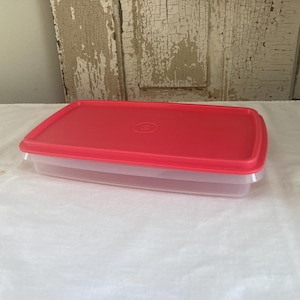 May include: A red plastic rectangular container with a clear lid. The container is made of durable plastic and is perfect for storing food.