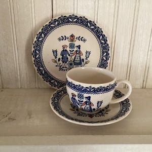 May include: A vintage ceramic tea set with a plate, saucer, and teacup. The set features a blue and white floral design with figures in traditional clothing. The plate is 8 inches in diameter.