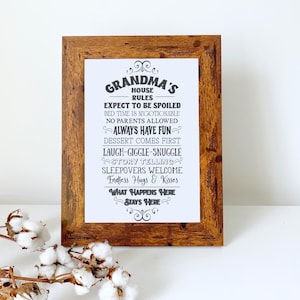 May include: A framed print with the text "Grandma's House Rules" in black on a white background. The frame is made of dark brown wood. The rules include "Expect to be spoiled" and "Always have fun."
