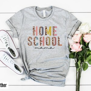 May include: Gray t-shirt with the text "HOME SCHOOL mama" in colorful letters with a leopard print pattern.