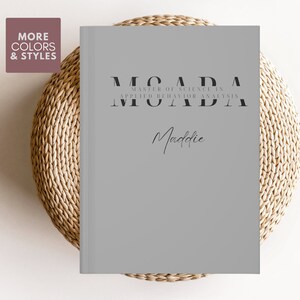 Puede incluir: Cuaderno gris con el texto "Master of Science in Applied Behavior Analysis" y el nombre "Maddie" escrito en cursiva.