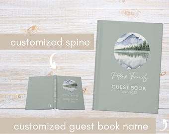 May include: A sage green guest book featuring a watercolour illustration of a mountain lake scene. The book is titled "Peter's Family Guest Book Est. 2023".