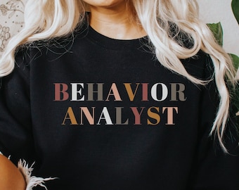 May include: Black sweatshirt with the text "BEHAVIOR ANALYST" in colourful block letters.