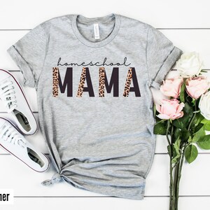 Op de afbeelding: Grijs T-shirt met de tekst "homeschool MAMA" in zwarte letters met een luipaardprint.