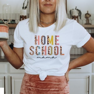 May include: White t-shirt with the text "HOME SCHOOL mama" in colorful letters with a leopard print pattern.