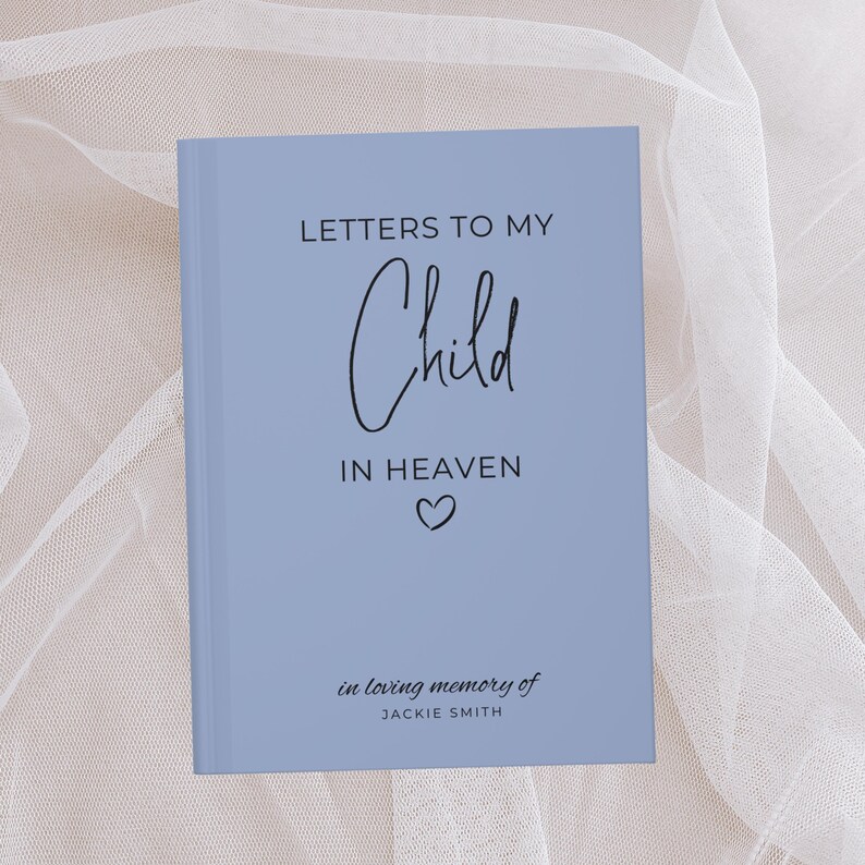 May include: A light blue journal with the text "Letters to My Child in Heaven" and a small heart symbol. The text "in loving memory of JACKIE SMITH" is at the bottom of the journal.