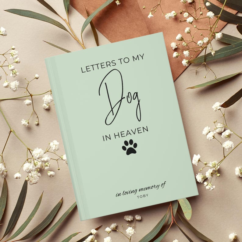 Peut inclure: Un journal vert clair avec le texte "Lettres &agrave; mon chien au paradis" et une empreinte de patte. Le texte "en souvenir affectueux de TOBY" est en bas du journal.