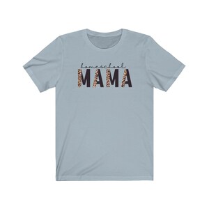 Op de afbeelding: Lichtblauw T-shirt met de tekst "homeschool MAMA" in zwarte letters. Het woord "MAMA" is bedrukt met een luipaardprint.