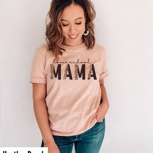 Op de afbeelding: Een heideperzikkleurig T-shirt met de tekst "homeschool MAMA" in zwart met een luipaardprint.