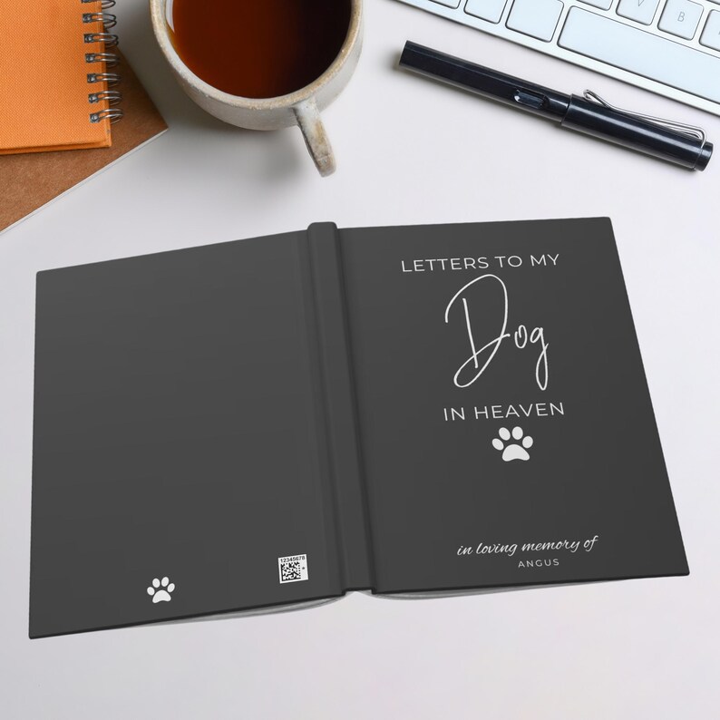 Peut inclure: Un journal noir avec le texte "Lettres &agrave; mon chien au paradis" et une empreinte de patte. Le journal a une empreinte de patte blanche sur la couverture avant et le texte "en souvenir affectueux d'Angus" sur la couverture arri&egrave;re.