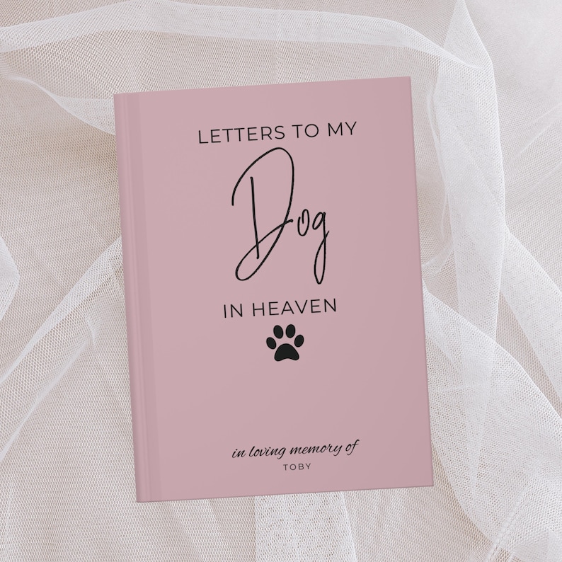 Peut inclure: Un journal rose avec le texte "Lettres &agrave; mon chien au paradis" et une empreinte de patte. Le journal porte le texte "en souvenir affectueux de TOBY" en bas.