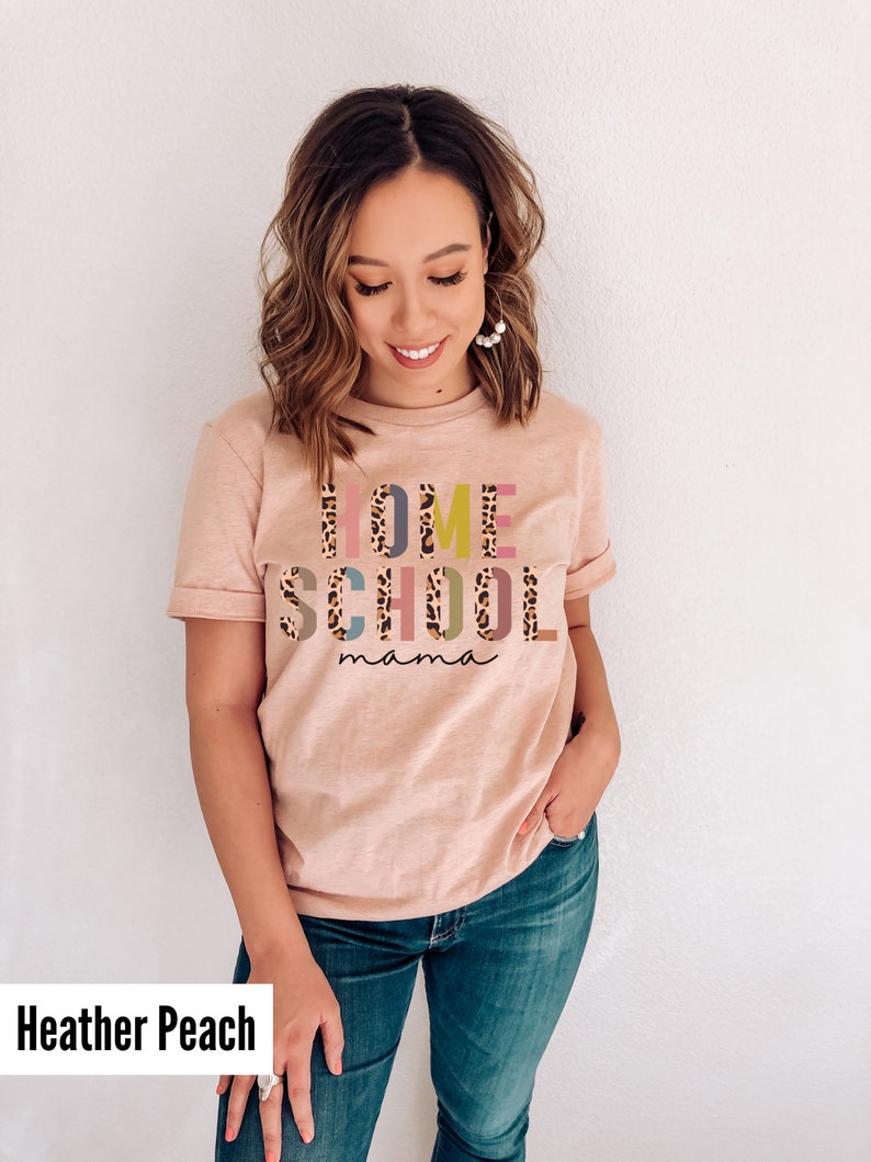 May include: A heather peach colored t-shirt with the text "HOME SCHOOL mama" in colorful letters with a leopard print pattern.