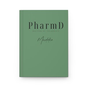 May include: A green book with the text "PharmD Doctor of Pharmacy Maddie" on the cover.
