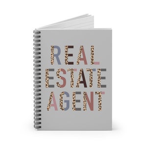 May include: A gray spiral notebook with the text "REAL ESTATE AGENT" in colorful letters with a leopard print pattern.