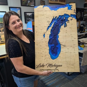 May include: A rectangular wooden bathymetric map of Lake Michigan featuring layered blue water depths and natural wood land topography. The map includes engraved road networks, the text Lake Michigan, and a scale bar labeled 0, 10, 20, 30, 40, 50.