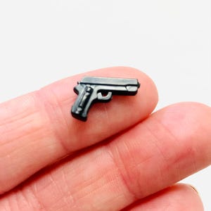 May include: A small, black plastic toy gun. The gun is about the size of a finger.