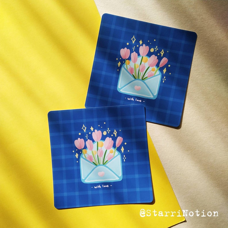 Puede incluir: Dos tarjetas a cuadros azules y blancos con un ramo de flores rosas y amarillas dentro de un sobre azul. El sobre tiene un coraz&oacute;n y el texto "with love" en &eacute;l.