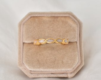 May include: A gold ring with a white and pink stone design. The ring is in a velvet ring box.