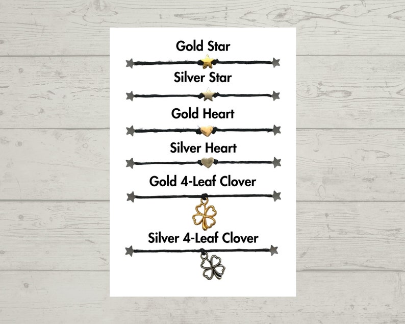 Puede incluir: Una tarjeta blanca con pulseras de cuerda negra con diferentes dijes. Los dijes incluyen estrellas doradas y plateadas, corazones y tr&eacute;boles de cuatro hojas. El texto en la tarjeta dice "Gold Star", "Silver Star", "Gold Heart", "Silver Heart", "Gold 4-Leaf Clover" y "Silver 4-Leaf Clover".