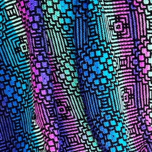 May include: A colorful crochet blanket with a geometric pattern in shades of blue, green, purple, and pink. The blanket is made with a variety of stitches and textures, creating a unique and eye-catching design.