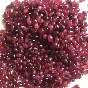 May include: A large pile of ruby red gemstone beads in a teardrop shape.